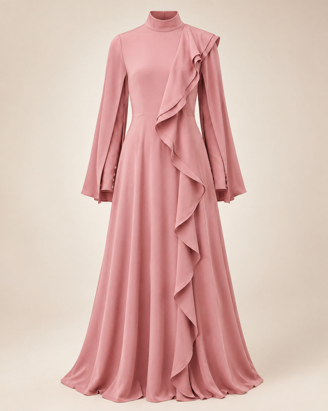 A dusty pink long-sleeve maxi dress with a mock neck, featuring a draped ruffle detail cascading down the right side of the skirt, displayed on a mannequin against a solid beige background.